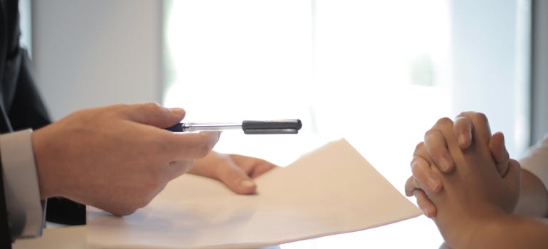 Woman receiving an insurance contract and a pen to sign.